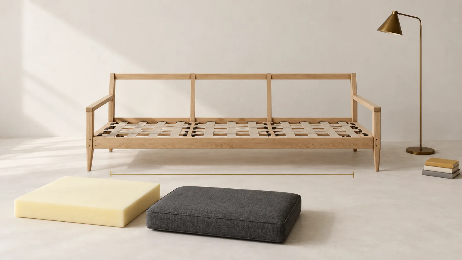 Ossature en bois d'un canapé avec ses sangles, à côté d'un bloc de mousse et d'un coussin