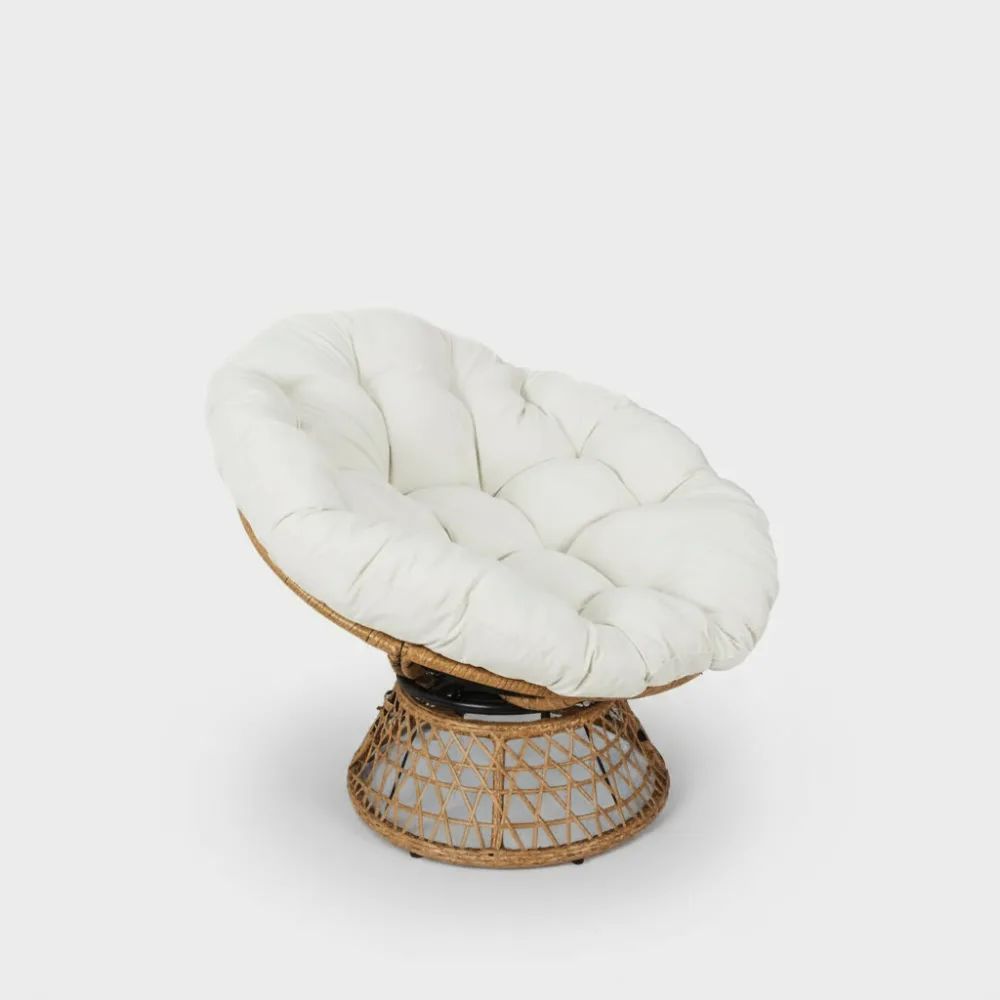 Fauteuil Cancun de Quel Canapé, en rotin avec coussin blanc capitonné, base ajourée circulaire, vue trois-quarts légèrement surélevée.
