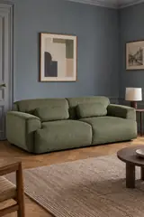Vue d'ensemble du canapé Wallas La Redoute 3 places en velours, coloris vert olive, style classique, dans un salon au mur bleu ardoise (mise en situation illustrée par IA)
