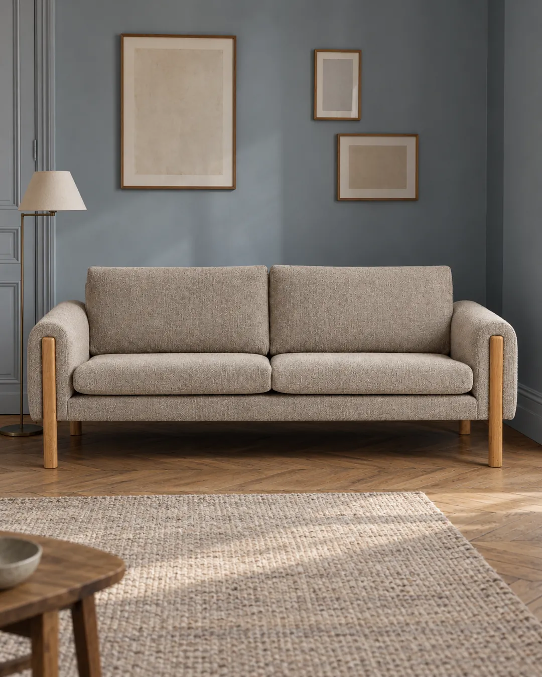 Plan rapproché du canapé Vino La Redoute 3 places en tissu, coloris beige, style scandinave, dans un salon au mur bleu ardoise (mise en situation illustrée par IA)