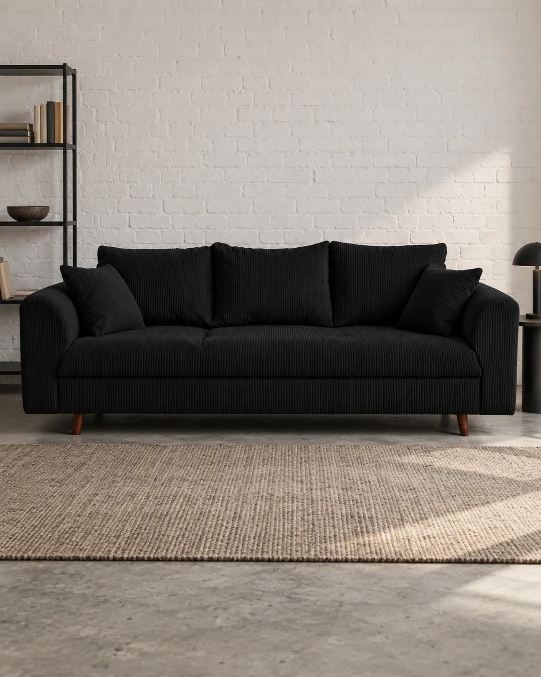 Plan rapproché du canapé Rune Maisons du Monde 3 places en velours, coloris noir, style vintage, dans un ancien atelier transformé en logement (mise en situation illustrée par IA)