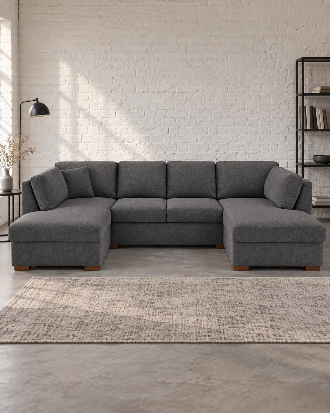 Plan rapproché du canapé Times Square Maisons du Monde 6 places convertible en tissu, coloris gris foncé, style contemporain, dans un ancien atelier transformé en logement (mise en situation illustrée par IA)