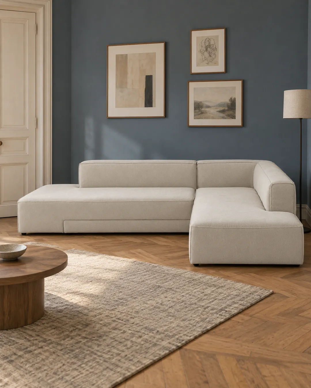 Plan rapproché du canapé Ginosa La Redoute d'angle convertible en tissu, coloris ivoire, style contemporain, dans un salon au mur bleu ardoise (mise en situation illustrée par IA)