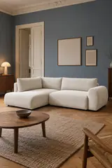 Vue d'ensemble du canapé Lucien Bobochic d'angle convertible en velours, coloris ivoire, style contemporain, dans un salon au mur bleu ardoise (mise en situation illustrée par IA)